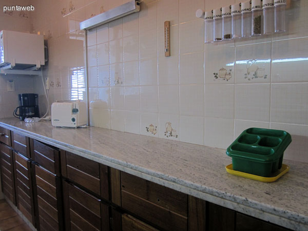 Mesada en la pared sur de la cocina. Acondicionada con muebles bajo y sobre mesada en madera y dos bachas.