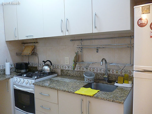 Kitchen. Inside. Equipped with table, furniture and low shelves and countertops, stainless steel sink.