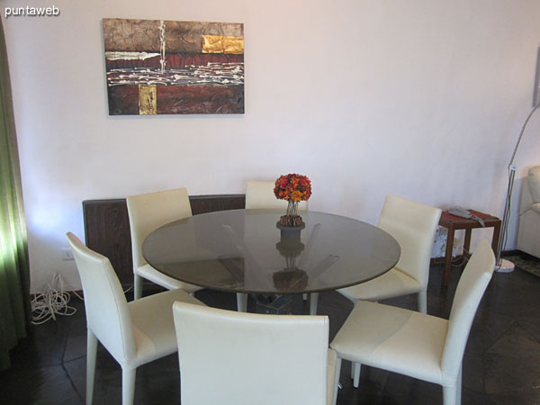 Overview of the first section of the living room from the right corner by the window. <br><br>In the foreground, conditioned dining space with round table and six chairs.