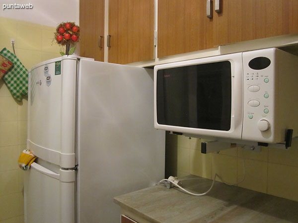 Kitchen. Interior. Fitted furniture on and under table, gas stove four burner stove, microwave and refrigerator.