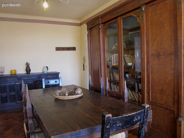 Detalle de mesa del comedor en madera con capacidad para 6 u 8 personas. Al fondo los accesos al dormitorio y a la cocina.