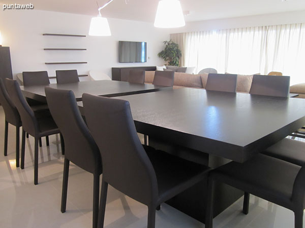 Defined space equipped with modern dining wood tables for 12 people.<br><br>To the right of the image, the kitchen visually connected  with the environment.