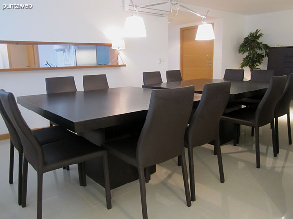 Espacio definido de comedor acondicionada con modernas mesas en madera para 12 personas.<br><br>A la derecha de la imagen, cocina conectada visualmente con el ambiente.