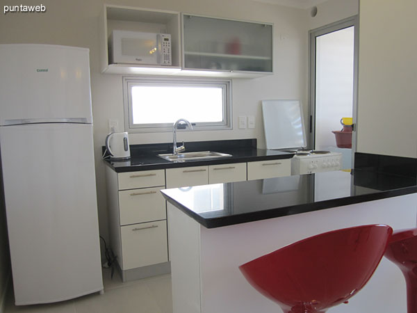 View from living room to the kitchen. In the background is seen the bar two modern kitchen chairs.