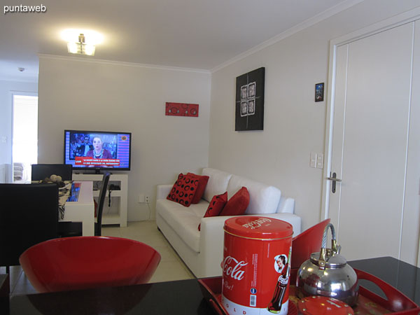 View of living room from the dining room from the right corner to the front door. <br><br>At the bottom of the image, kitchen with bar in black.