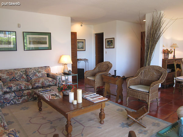 Overview of room in the living room. Conditioning a chair three bodies, one of two, two wicker armchairs and two wooden chairs around a low wooden rectangular table.