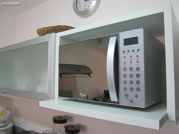 Vista general de la cocina hacia el sector de la heladera, horno microondas y estantes en altura.