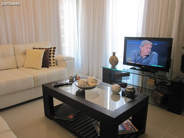 Ambiente de living acondicionado con dos sillones de dos cuerpos en torno a una mesa baja en madera.