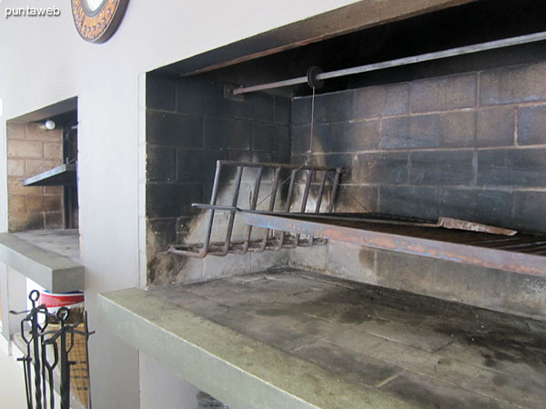 Barra en madera frente a los parrilleros con tres taburetes altos en madera y mimbre.