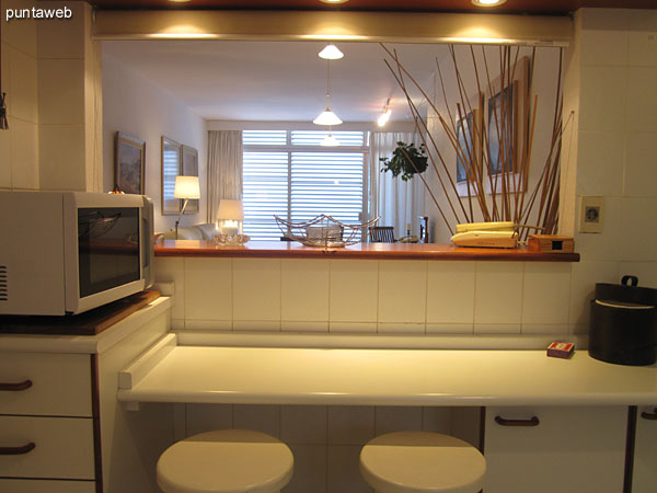 Detalle de barra con mesa a modo de desayunador.<br><br>Acondicionada con dos banquetas de madera blancas.