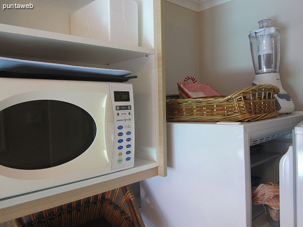 Detail of kitchen equipment on which is: Four burner electric stove, microwave, toaster and fridge.