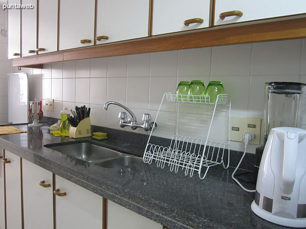 Detalle de los estantes en la cocina y mesa contra la pared con dos sillas como desayunador.<br><br>Disposicin del horno microondas.