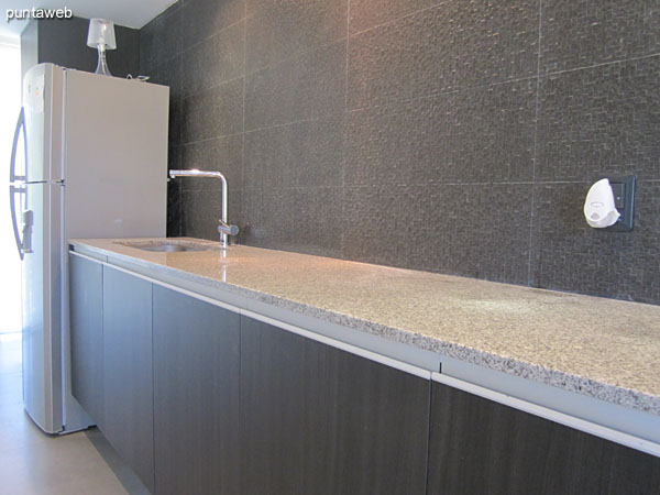 Kitchen. Partially integrated into the living room through a bar.<br><br>Equipped with gray granite countertop, under counter and double sink.