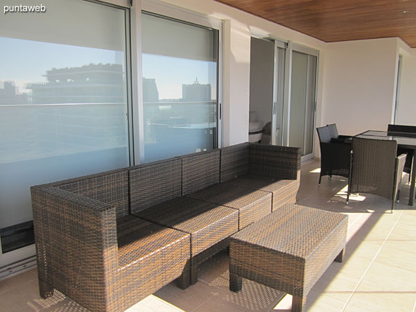 Vista general del balcn terraza del apartamento. Accesible desde todos los ambientes del apartamento.<br><br>Equipado con mesa rectangular en vidrio y smil rattn con seis sillas, silln de tres cuerpos y otros elementos de estar.