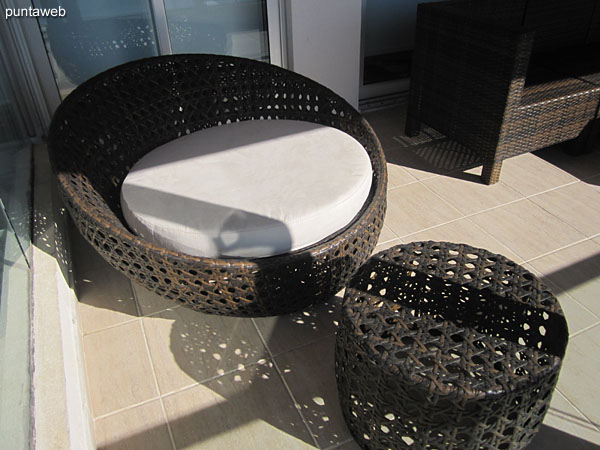 Detail of three bodies armchair in rattan simile in the apartment balcony terrace.