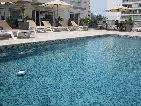 Outdoor pool located on second floor level. It has solarium space with sun loungers and umbrellas.