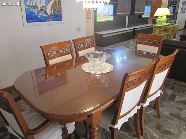 Detalle de la mesa de comedor en madera y vidrio con seis sillas.