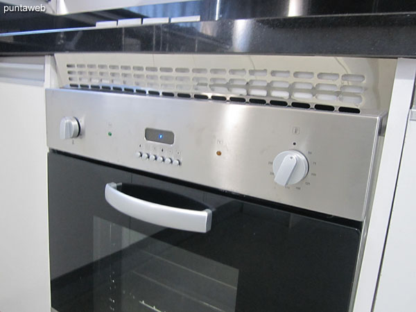 Detalle de equipamiento de la cocina: anafe eléctrico de cuatro hornallas con campana extractora y horno eléctrico empotrado.