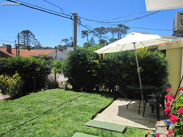 Espacio de estar en el jardn del apartamento equipado con mesa, sillas y sombrilla.