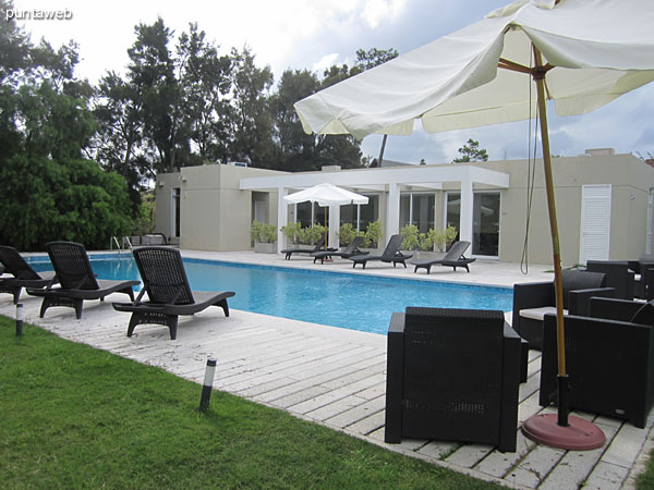 The space surrounding the outdoor pool has lounge chairs, chairs and umbrellas.