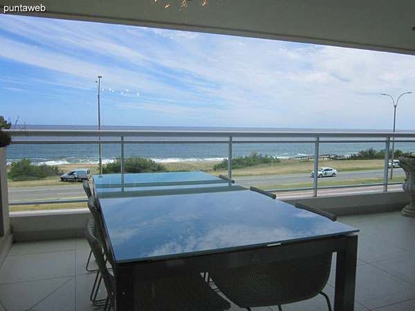 Access to the terrace balcony of the apartment. It has a barbecue, rectangular glass table with six chairs.