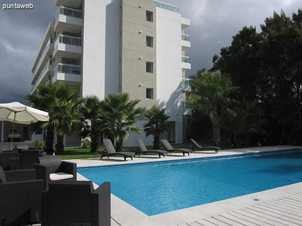 The space surrounding the outdoor pool has lounge chairs, chairs and umbrellas.