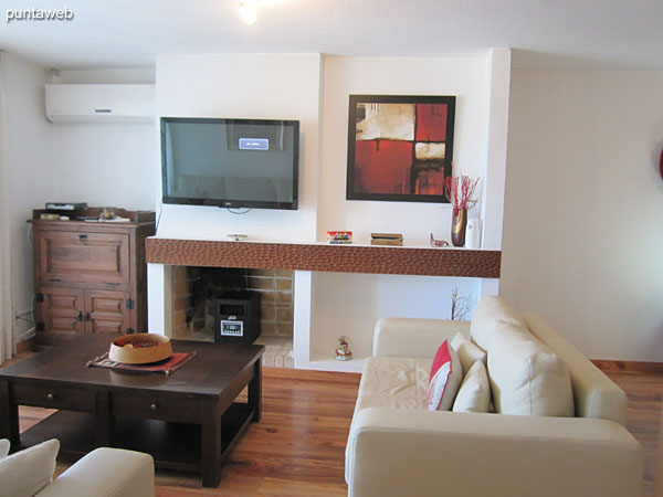 Living environment in the living room. It has TV with cable, air conditioner, armchair of two bodies and armchair of three bodies in L around a low table in wood.