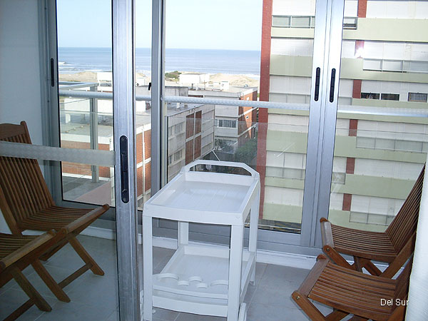 Terraza exterior con cerramiento de vidrio y aluminio, con muebles de terraza.