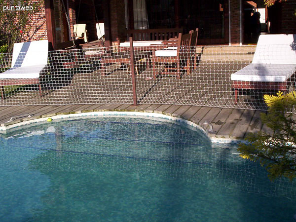 Perímetro de seguridad al final del deck de madera en torno a la piscina al aire libre climatizada.<br><br>A la izquierda y fondo de la imagen el jardín frontal de la casa cercado en el perímetro con arbustos que brindan gran privacidad. 