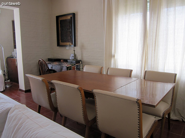 Espacio de comedor en el lateral del ambiente. Acondicionado con importante mesa rectangular con seis sillas tapizadas a juego.