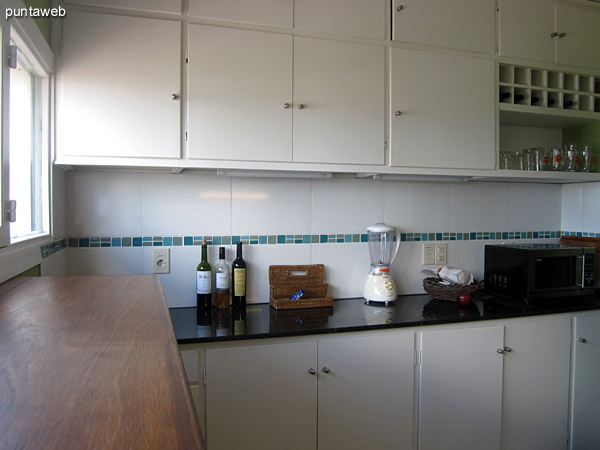 General view of the kitchen. Located on the front of the apartment is fitted out with furniture under table and equipped with gas stove, range hood, double sink, large refrigerator, microwave, blender, etc.