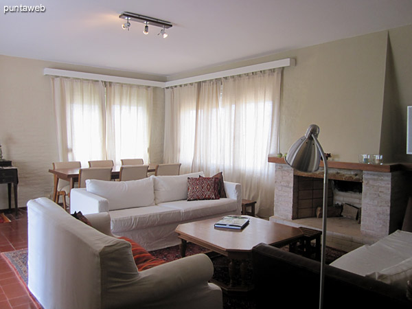 General view of the living room. Conditioning with fireplace and furnished with three chairs one, two and three bodies around a low table in wood.