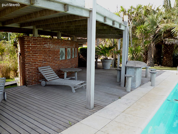 Deck solarium prximo a la piscina, mesa y bancos en madera.<br>Mobiliario de exterior haciendo juego.