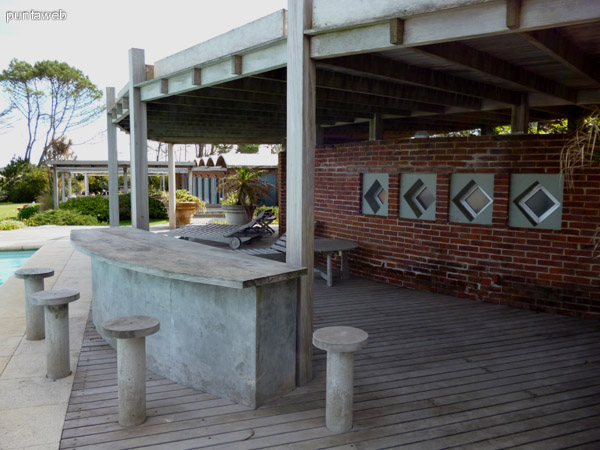 Barra, deck solarium y reposeras prximos a piscina.